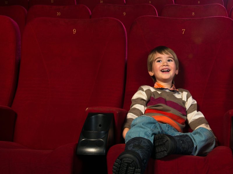 Smiling little boy watching movie in a cinema Smiling little boy watching movie in a cinema